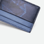 Porte-cartes en cuir et toile bleu incliné pour observer les détails.